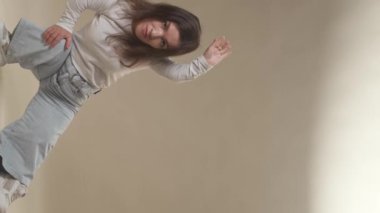 Beyaz tenli genç bir kadının dikey portresi. Cüce görünüşlü. Kameraya bakıyor.