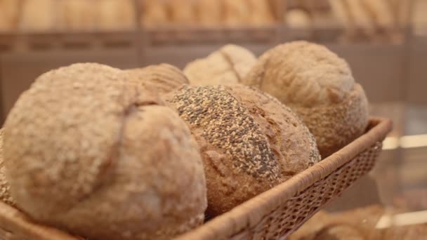 パン屋で展示されているわらトレイにゴマの種子が横たわる新鮮なパンの丸みを閉じる人はいません — ストック動画