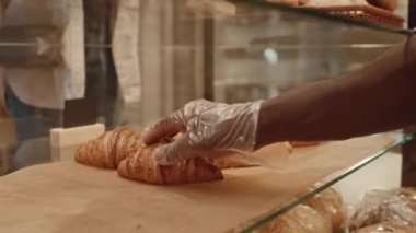 Fırın işçisinin tanınmayan eldiveni taze kruvasanı vitrinden çıkarıp müşteriye verdiği görüntüler.