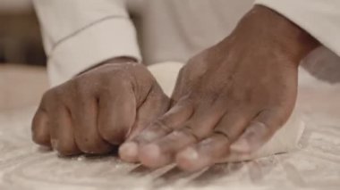 Pastanede ekmek yaparken hamur yoğuran fırıncının tanınamaz hale gelen siyah erkek ellerine yakın çekim