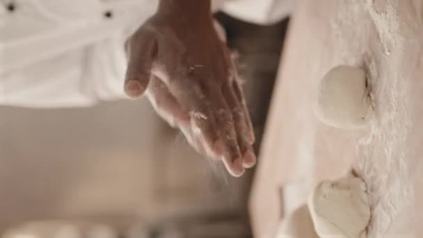 アフリカ系アメリカ人男性パン屋の手がパン生地の丸い形状をパン屋のテーブルに作る垂直なクロップショット — ストック動画