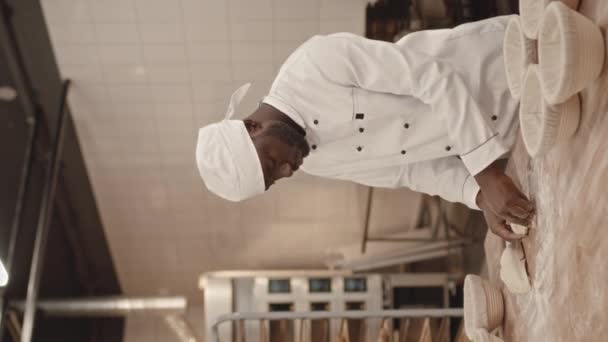 キッチンのパン屋のためのパンを作っている間 白い調理工芸品の労働ウェアの若い黒人の縦の媒体のショット — ストック動画