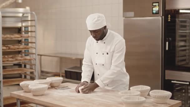身着白色厨师制服的年轻非洲裔美国男性烘培者 站在工作台前揉搓和塑造面团时 对着相机微笑的中影 — 图库视频影像