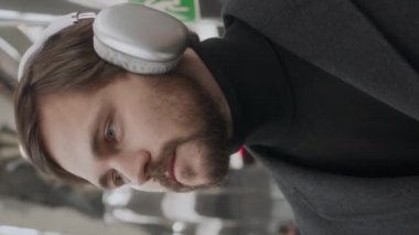 Kafkas kökenli genç sakallı adamın dikey göğsü radyo kulaklığıyla müzik dinlerken istasyonda metro istasyonunu bekliyor.