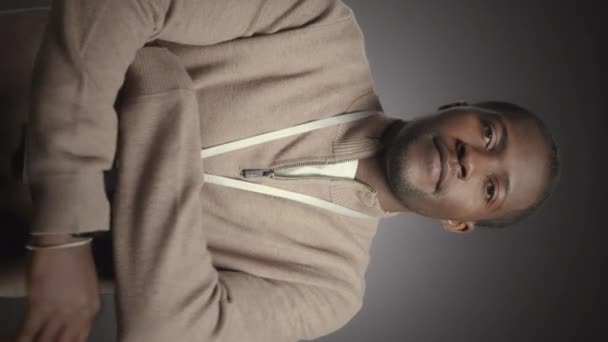 年轻的非洲裔美国人 脖子上戴着身份证 双手交叉在灰色的摄影棚背景上对着相机摆姿势 他的垂直中速肖像 — 图库视频影像