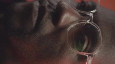 Siyah erkek programcının gözlüklerine yansıyan yeşil programlama kodunun dikey olarak kapatılması