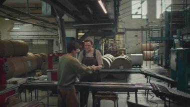 Matbaada üretim bandında çalışan iki farklı etnik çeşitlilikte kadın fabrika işçisi.