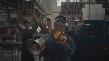 Aktif Afrikalı genç Amerikalı bir kadının grev sırasında ellerinde gösteri pankartlarıyla protesto sloganları attığı orta boy bir fotoğraf.
