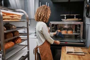 Kadın fırıncı taze ekmekle tepsiyi serinletmek için alıyor.