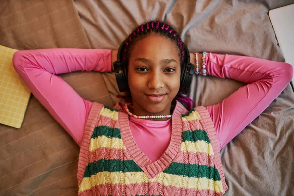 Yatakta Uzanmış Pembe Giyinmiş Kulaklıkla Müzik Dinleyen Siyahi Genç Bir — Stok fotoğraf