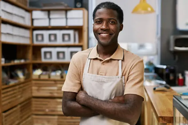 Portrait of positive Black bakery worker standing with arms crossed