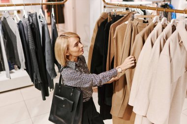 Alış veriş merkezinde elbise raflarında gezen zarif genç bir kadının yan görünüm portresi, fotokopi alanı