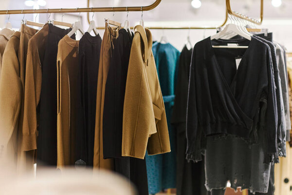 Background image of Autumn fashion collection on rack in clothing boutique, copy space