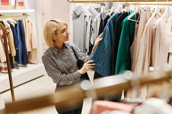 Side view portrait of elegant young woman choosing clothes in luxury boutique, copy space