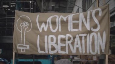 İşyerinde protesto gösterileri düzenleyen, sloganlar atan ve grev posterleri taşıyan dört kararlı etnik çeşitliliğe sahip feministin orta boy çekimi.