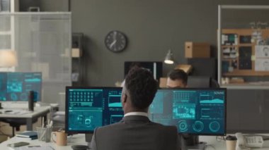 Ajansta çalışan farklı etnik çeşitlilikte erkek siber güvenlik memurlarının orta boy görüntüleri, birden fazla bilgisayar ekranında gizli veri bilgileri ve ağ sistemini izleyen klasörler