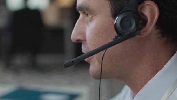 专业白种人男性网络安全特工通过一个耳机向同事传递信息的中等特写镜头 背景模糊 — 图库视频影像