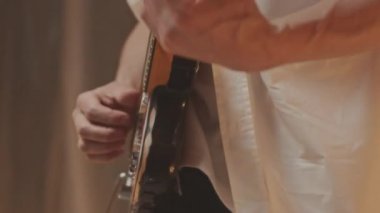 El yapımı müzik stüdyosunda, polietilen çarşaflardan yapılmış duvarlarla modüler sentezleyiciyle elektronik gitar çalan tanınmayan bir erkek müzisyenin eğik çekimi.