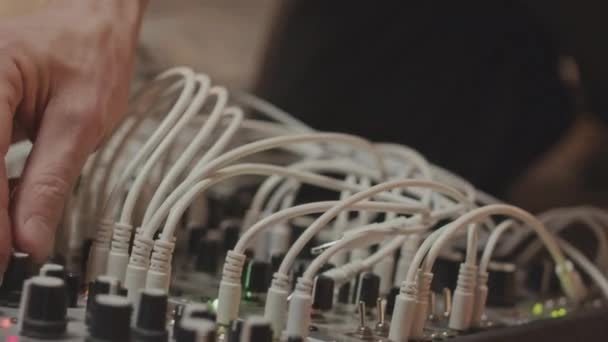 年轻的白人男性音乐家在工作室创作音乐的同时 将多个音频电缆连接到专业模块化合成器的倾斜向上截图 — 图库视频影像