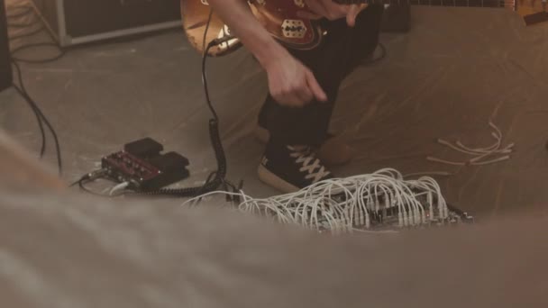 白人男性吉他手将电吉他插进模块化合成器中 同时在80年代风格的工作室中制作新音乐的倾斜镜头 — 图库视频影像