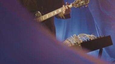 Kafkasyalı sakallı genç gitaristin yavaş yavaş her yerde politen çarşafları olan ve konser provası yaparken elektro gitar çalan yeraltı neon stüdyosunda durması.