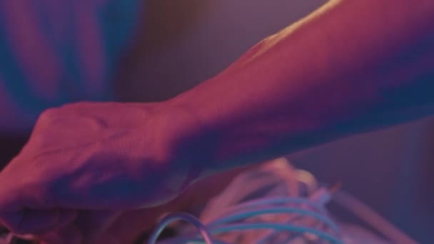 モジュラーシンセサイザーを使用してナイトクラブでネオンステージでテクノを演奏する白人男性音楽パフォーマーの撮影 — ストック動画