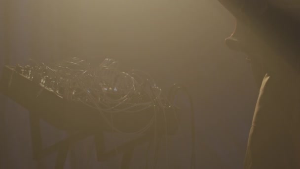 ダークスモーキーネオンスタジオでイエロープロジェクターライトの下に立っているエレクトリックギターを演奏する認識できない男性のシルエットの低角度傾斜 — ストック動画