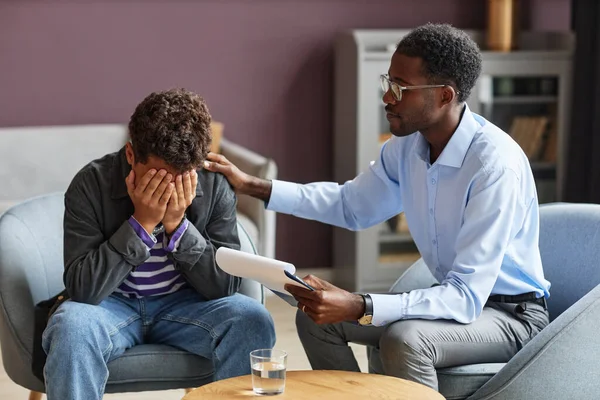 School psychologist supporting teenage boy crying after getting bullied