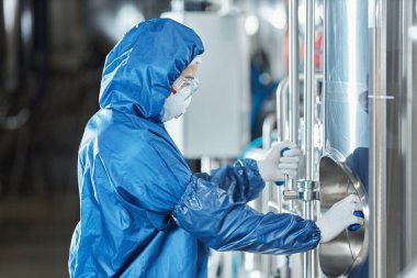 Kimya fabrikasında ekipman kullanırken koruyucu giysili kadın işçilerin yan görüş portresi