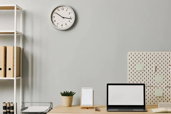 Minimal office setup with laptop screen mockup on desk by pastel blue wall, copy space