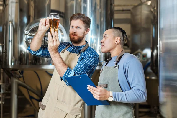 醸造工場で生産品質を検査しながらビールグラスを保持する醸造師の肖像画を待って コピースペース — ストック写真