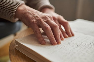 Masada kitap okumak için ellerini kullanan yaşlı kör bir adamın yakın çekimi.