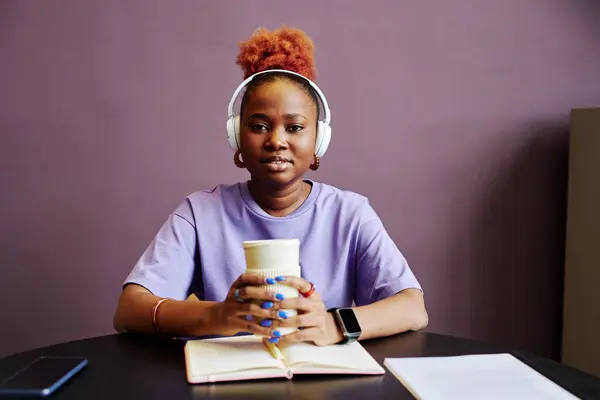 Minimal portrait of young black woman wearing headphones in minimal purple interior