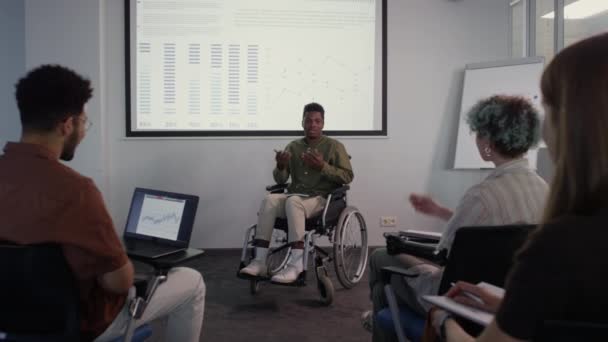 Pełne Ujęcie Młodego Afroamerykanina Wózku Inwalidzkim Wskazującego Wykres Ekranie Projektora — Wideo stockowe
