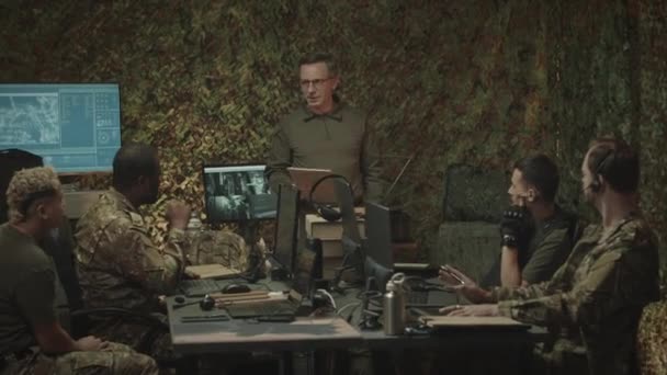 白人军事监视官员与多族裔工人小组一起坐在计算机前工作 夜间工作的中景照片 — 图库视频影像
