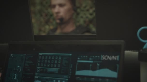 身穿迷彩服和战术背心的伯利兹年轻军官在办公室工作时 利用计算机监控程序 并通过耳机传输数据 — 图库视频影像
