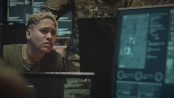 デスクでコンピュータで座って 同僚とカモフラージュの制服を着たサイバーセキュリティ監視プログラムについて話し合う白人女性軍人労働者 — ストック動画
