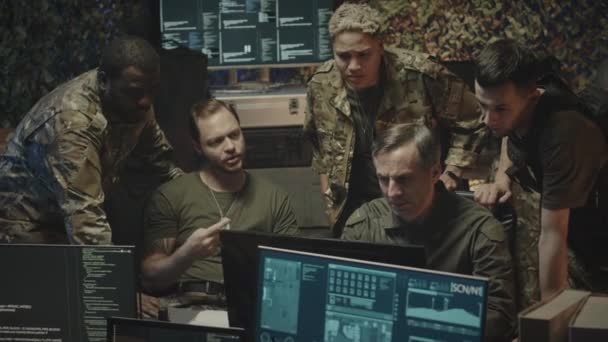 不同族裔的男性和女性军事网络安全工作者在夜间观看计算机显示数据并在黑暗的办公室进行讨论时拍摄的中景照片 — 图库视频影像