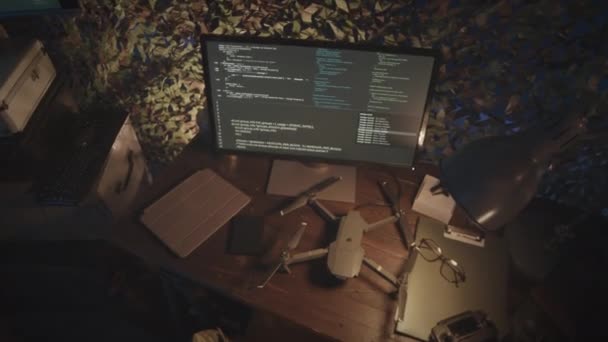 ダークコントロールセンターオフィスのテーブル上のコンピュータディスプレイと軍用ドローンの実行プログラミングコードのトップビューズームインショットはありません — ストック動画