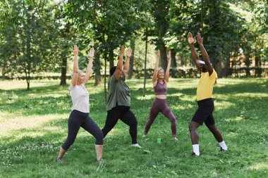 Parkın dışında spor yapmaktan hoşlanan yaşlı kadınların tam boy portresi. Erkek antrenör, esneme egzersizleri yapıyor ve yardımcı oluyor.