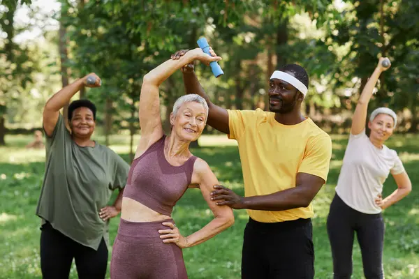 Waist up portrait of male sports trainer assisting senior woman enjoying outdoor sports workout in park