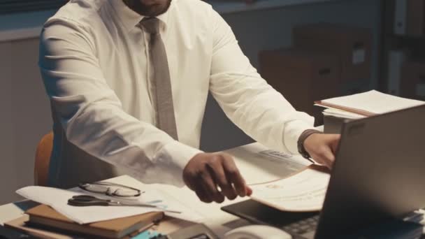 夜勤のオフィスデスクに座っている間 彼の資格の卒業証書をフレームに置くワークホリックブラックビジネスマンのクロップショット — ストック動画