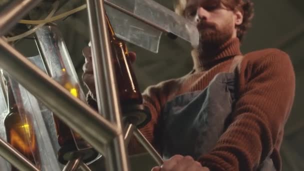 ビールのびん詰め機械装置を使用するひげを付けられたコーカサスの醸造所の技術者の低い角度のショット — ストック動画