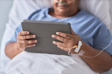 Hastane yatağında yatarken elinde dijital tablet tutan siyahi kadına yaklaş.