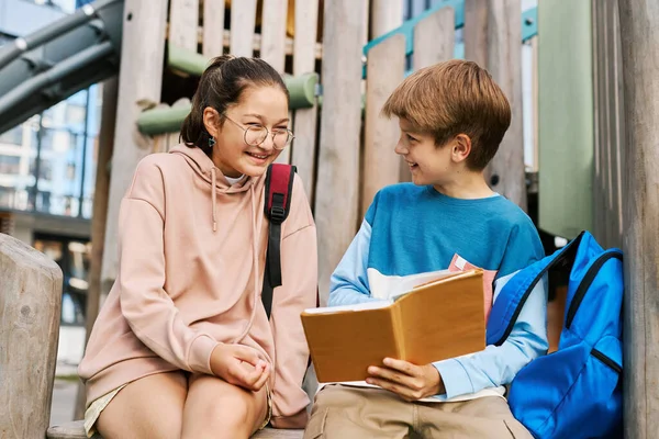 Happy Clever Schoolchildren Sitting Playground Equipment Discussing Plot Book Held — Stock Photo, Image