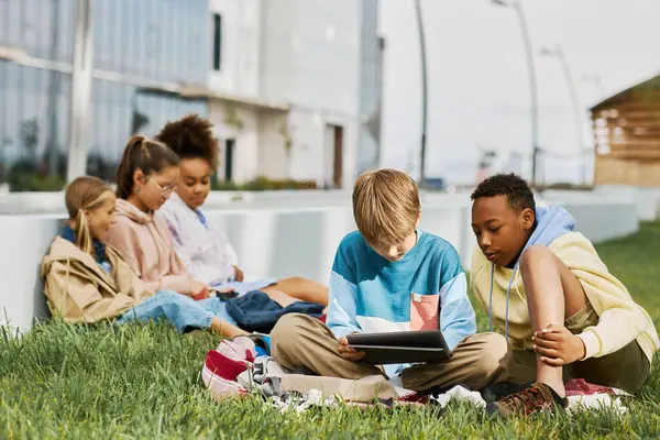 Two Intercultural Schoolboys Looking Tablet Screen While Sitting Green Lawn — Stock Photo, Image