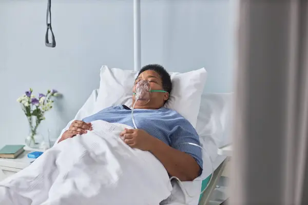 Portrait of senior African American woman laying on bed in hospital room with oxygen support