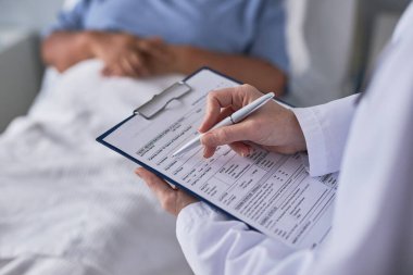 Hastane odasındaki hasta dosyalarını dolduran genç bayan doktoru kapatın.