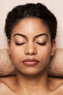 Genç siyahi kadın güzellik salonunda yüz ve vücut masajı yaptıktan sonra dinleniyor.