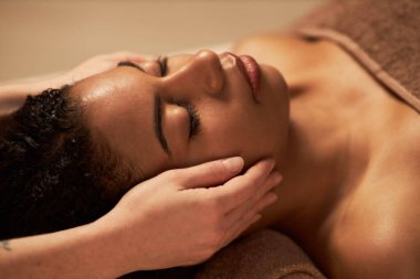 Genç bir kadın güzellik salonunda yüz masajı yaptırıyor.